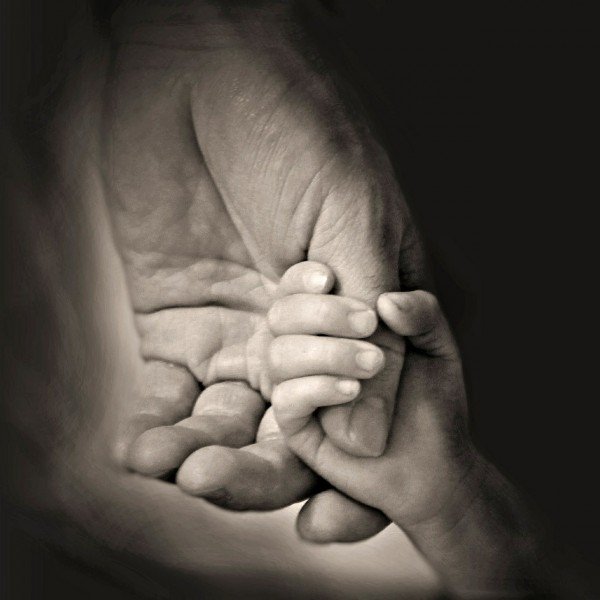 Adult hand with child holding thumb