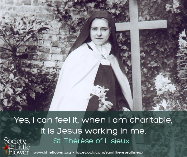 Photo of St. Therese of Lisieux, holding an Easter lily, in the garden at Le Carmel monastery,  before a wooden cross.
