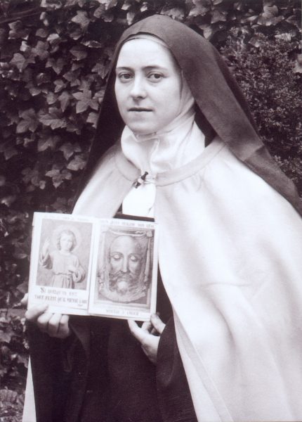 Photo of St. Therese holding a pamphlet depicting the Child Jesus and the Holy Face.