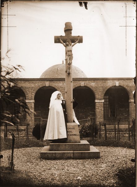 Photo of St. Therese as a novice, embracing the Crucifix in the courtyard at the convent in Lisieux.