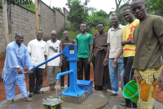 carmelites and villagers standing at new water pump for their village