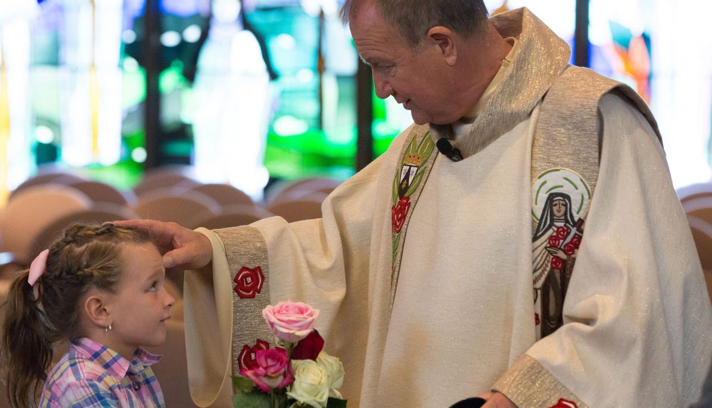 Fr. Bob Colaresi, blessing a child at the Feast Day Celebration