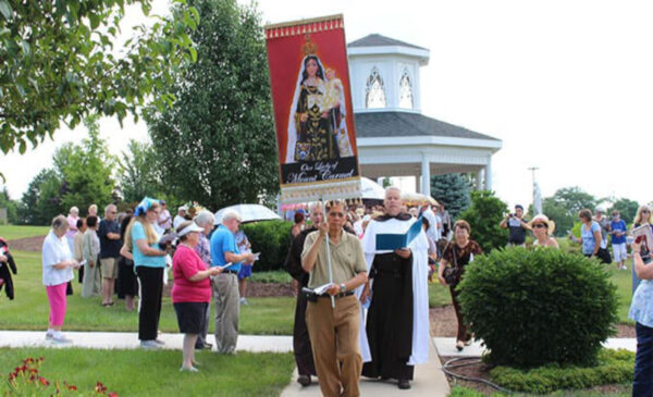 Priest and participants carry Our Lady of Mount Carmel banner and statue during annual procession