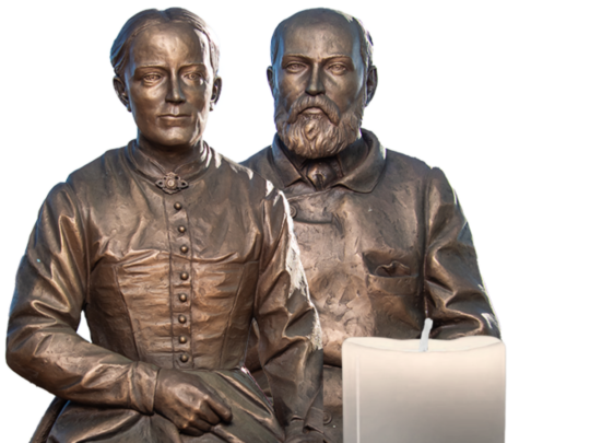 Bronze statue of Saints Louis and Zelie Martin with a candle