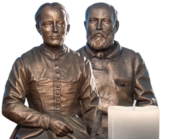 Bronze statue of Saints Louis and Zelie Martin with a candle